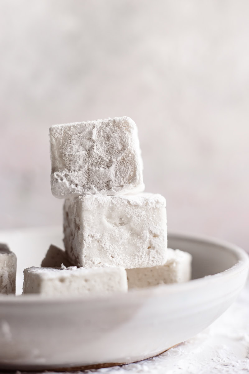 square vegan marshmallows stacked on top of one another in a bowl