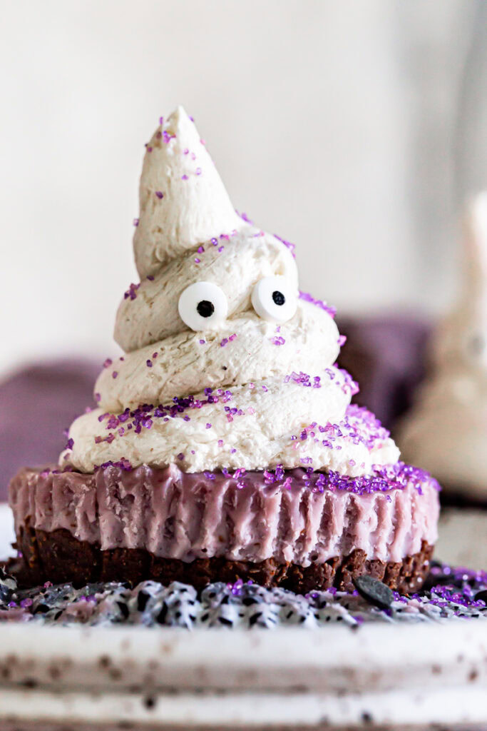 close up of a cheesecake ghost on a plate in the middle of the frame with a purple linen towel in the background.