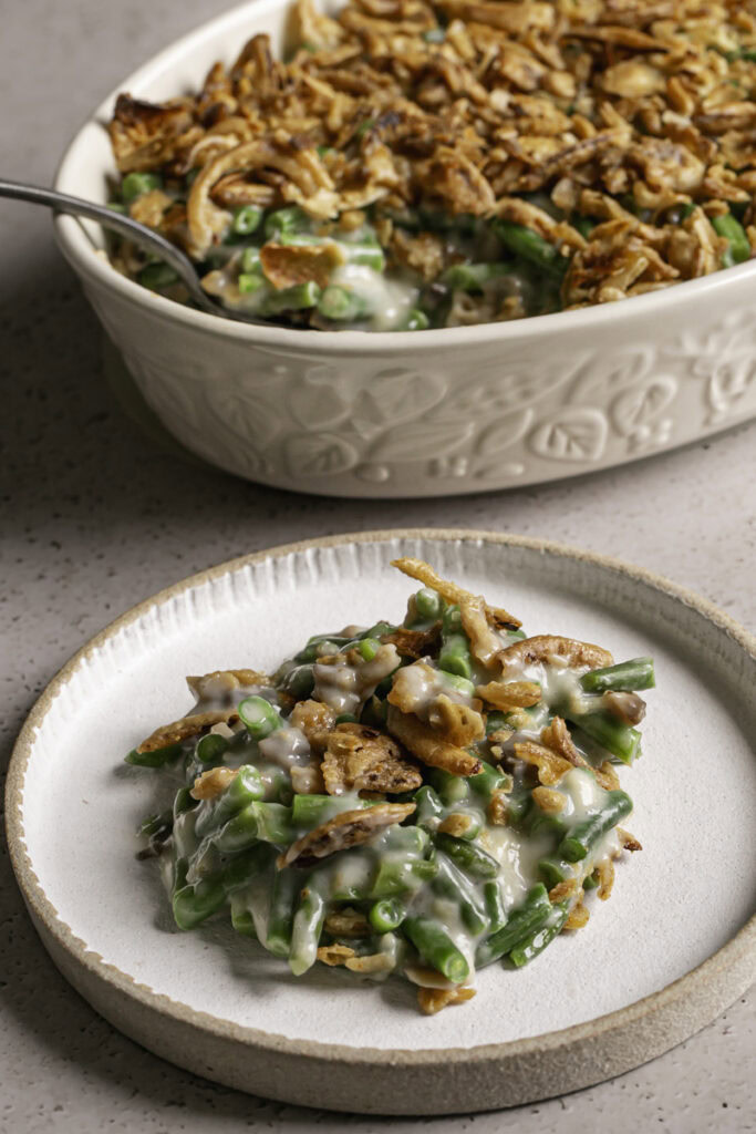 a plate of green bean casserole with the casserole dish in the background