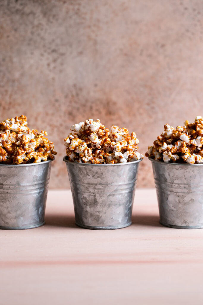 three buckets of caramel popcorn lined up next to each other