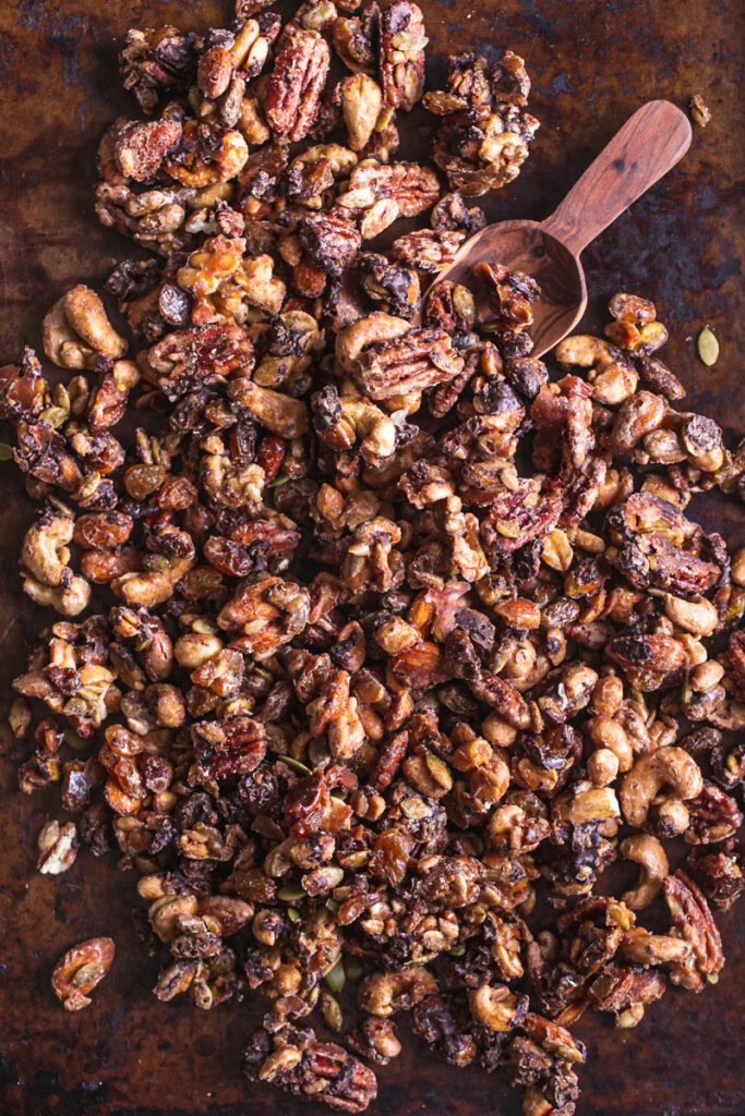 trail mix on a baking sheet with a wooden scoop