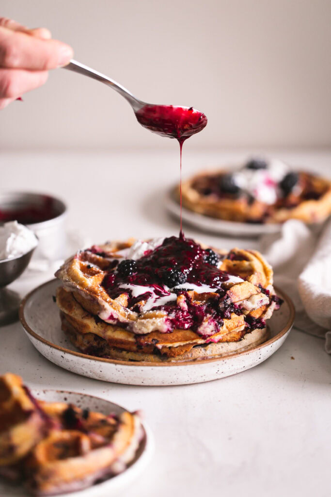 a side action shot of drizzling blackberry syrup over the waffles