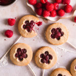 flat lay image of raspberry pie pops with a plate of raspberries and a small saucepan of raspberry preserves