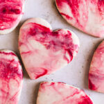 close up of heart shaped sugar cookies with red, pink and white marble icing