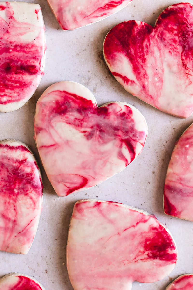 close up of heart shaped sugar cookies with red, pink and white marble icing