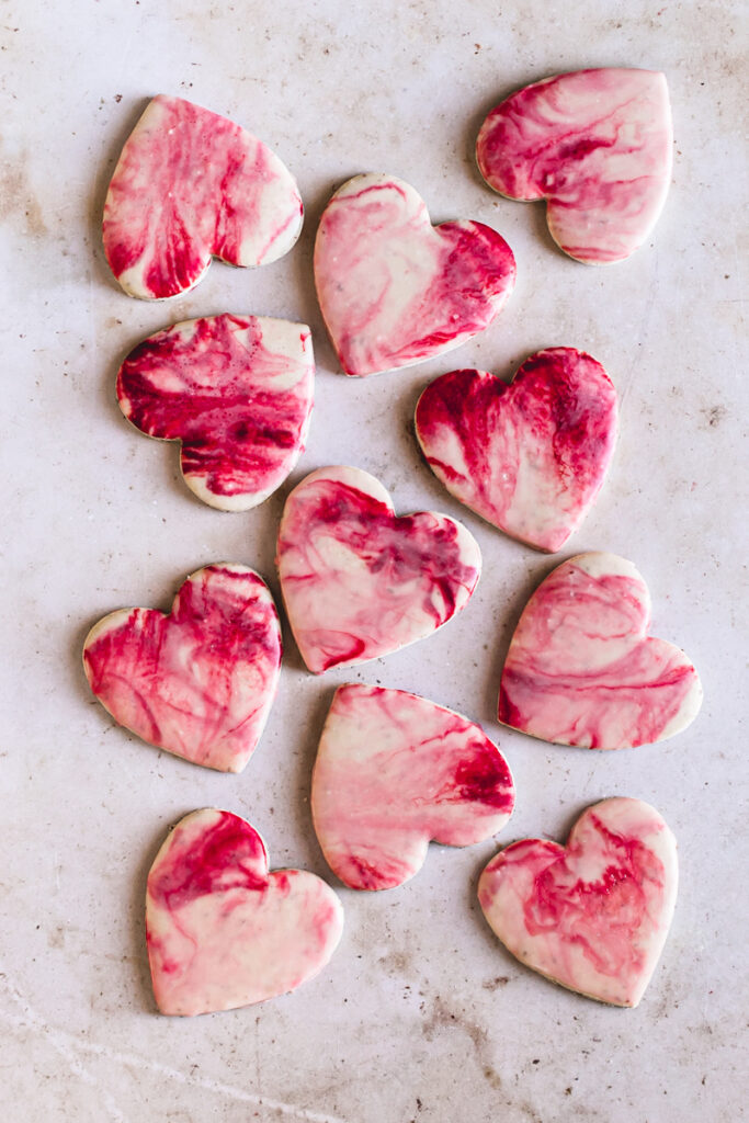 11 heart shaped sugar cookies with red, pink and white marble icing