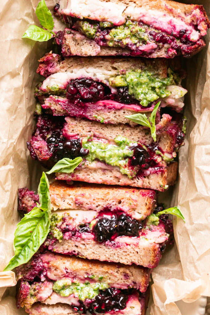 a flatlay image of sliced vegan blackberry pesto grilled cheese stacked together in a loaf pan