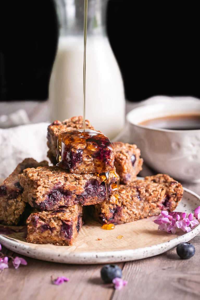 blueberry oatmeal French toast sticks on a plate with an action shot of maple syrup being poured over them