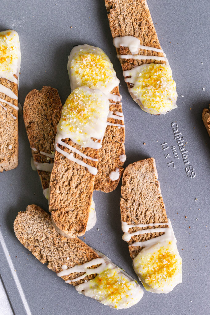 lemon vanilla biscotti piled on top of each other on a Calphalon cookie sheet