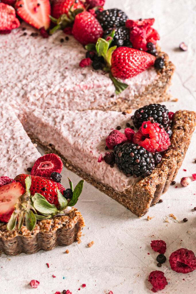 close up side view of breakfast chia yogurt granola tart decorated with fresh berries sliced