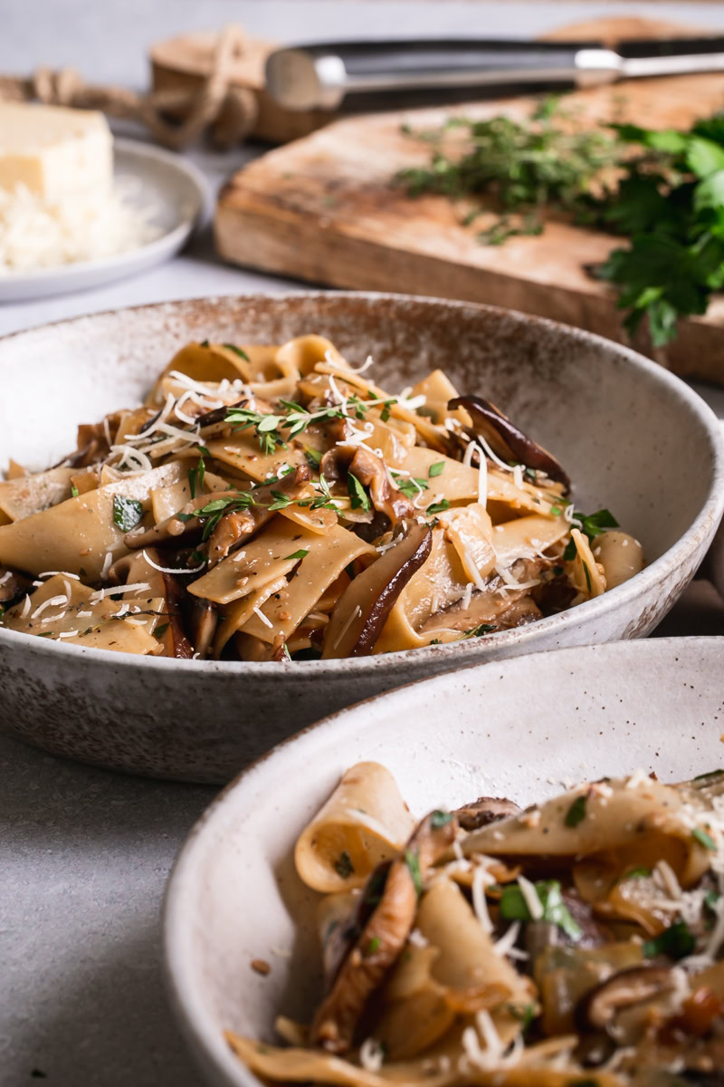 ide view of two bowls of gluten-free pappardelle with wild mushroom Ragù.