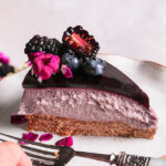 a side view of a slice of haskap berry cheesecake with a fork on a plate