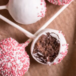 close up flatlay shot of no bake cherry cake pops, one with a bite taken out of it
