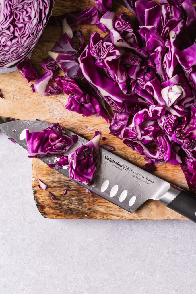 Calphalon 6" santoku knife on a cutting board with chopped red cabbage 