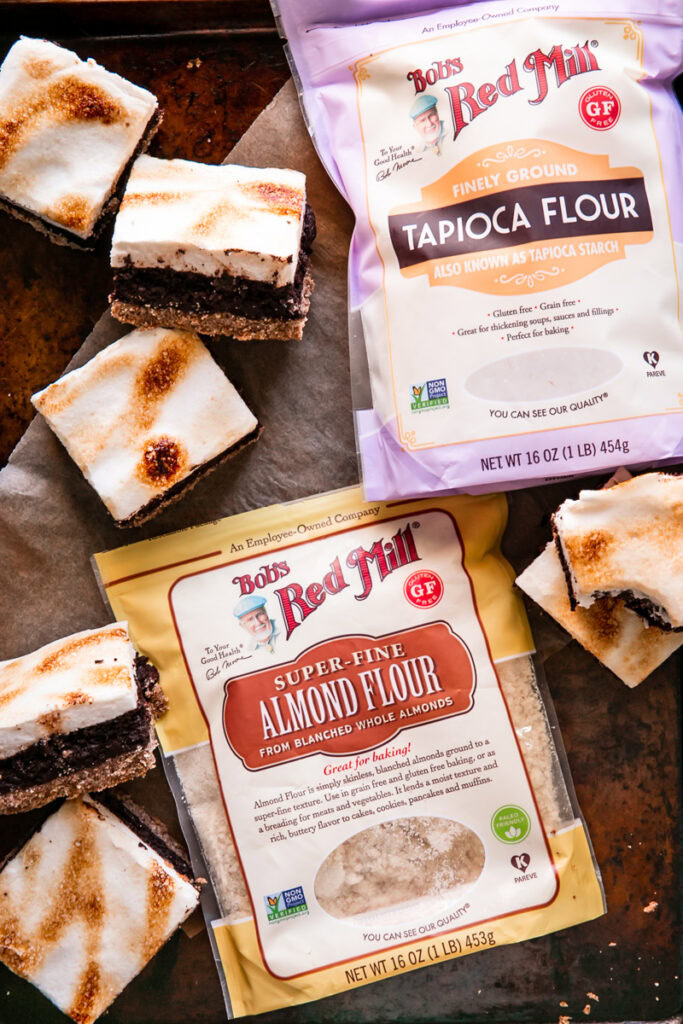flatlay image of Bob's Red Mill Tapioca flour and almond flour with s'mores brownies all around it on a baking sheet