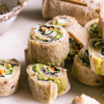 3/4 shot of sliced eggie sushi sandwich rollups stacked on top of each other