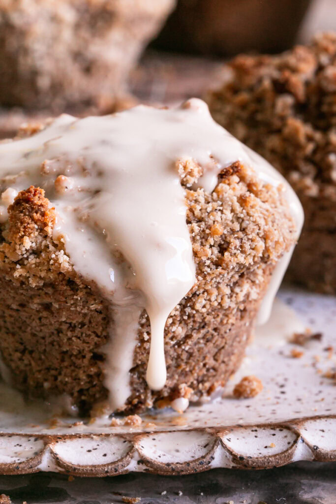close up of frosted cinnamon streusel muffin with icing dripping off of it