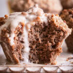 close up of a frosted cinnamon streusel muffin with a bite taken out of it