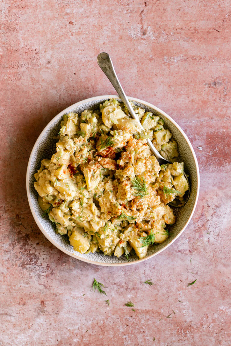 a bowl of smoked paprika dill potato salad with a serving spoon in it