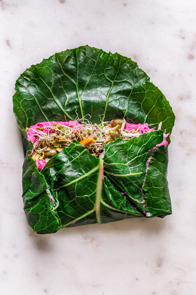 a half folded collard wrap filled with all of the fillings to show how to roll it