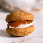 a single pumpkin spice latte whoopie pie with caramel dripping over the buttercream frosting