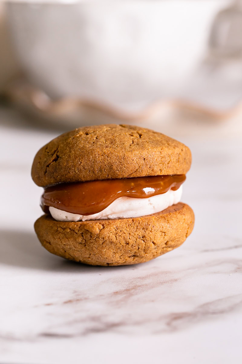 a single pumpkin spice latte whoopie pie with caramel dripping over the buttercream frosting
