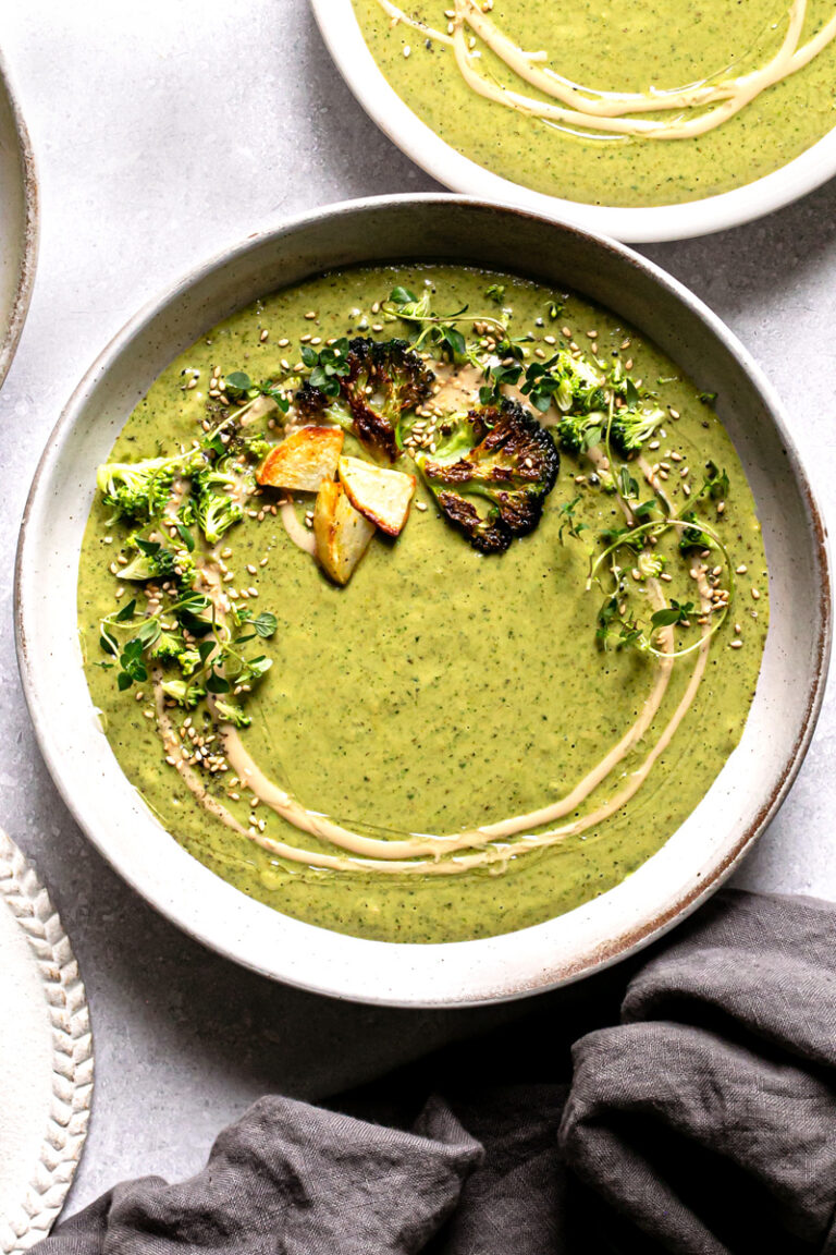 a single bowl of roasted broccoli potato tahini soup with a napkin below it