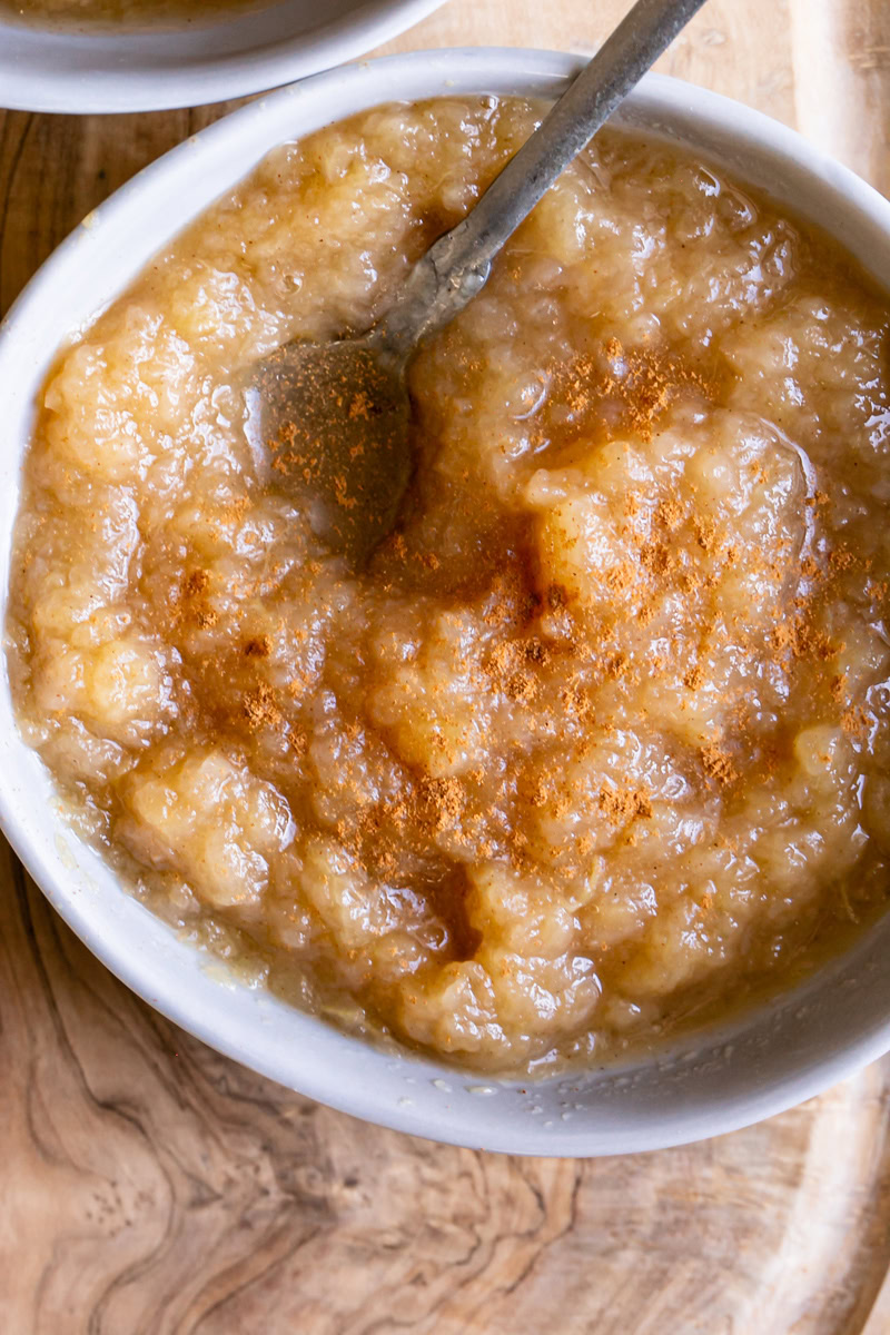 a close up of a bowl of Golden Delicious Applesauce with a spoon in it