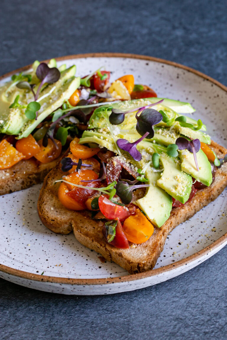 close up 3/4 view of two slices of Bruschetta Avocado Toast on a plate