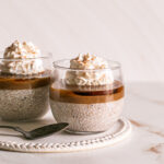 two glasses of caramel eggnog chia pudding topped with vegan caramel, maple syrup and whipped cream
