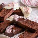 3/4 close up shot of Gluten-Free Chocolate Peppermint Biscotti with a plate of crushed peppermints in the background