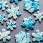 a close up of blue and white decoratedgrain-free marbled snowflake sugar cookies on a Calphalon baking sheet