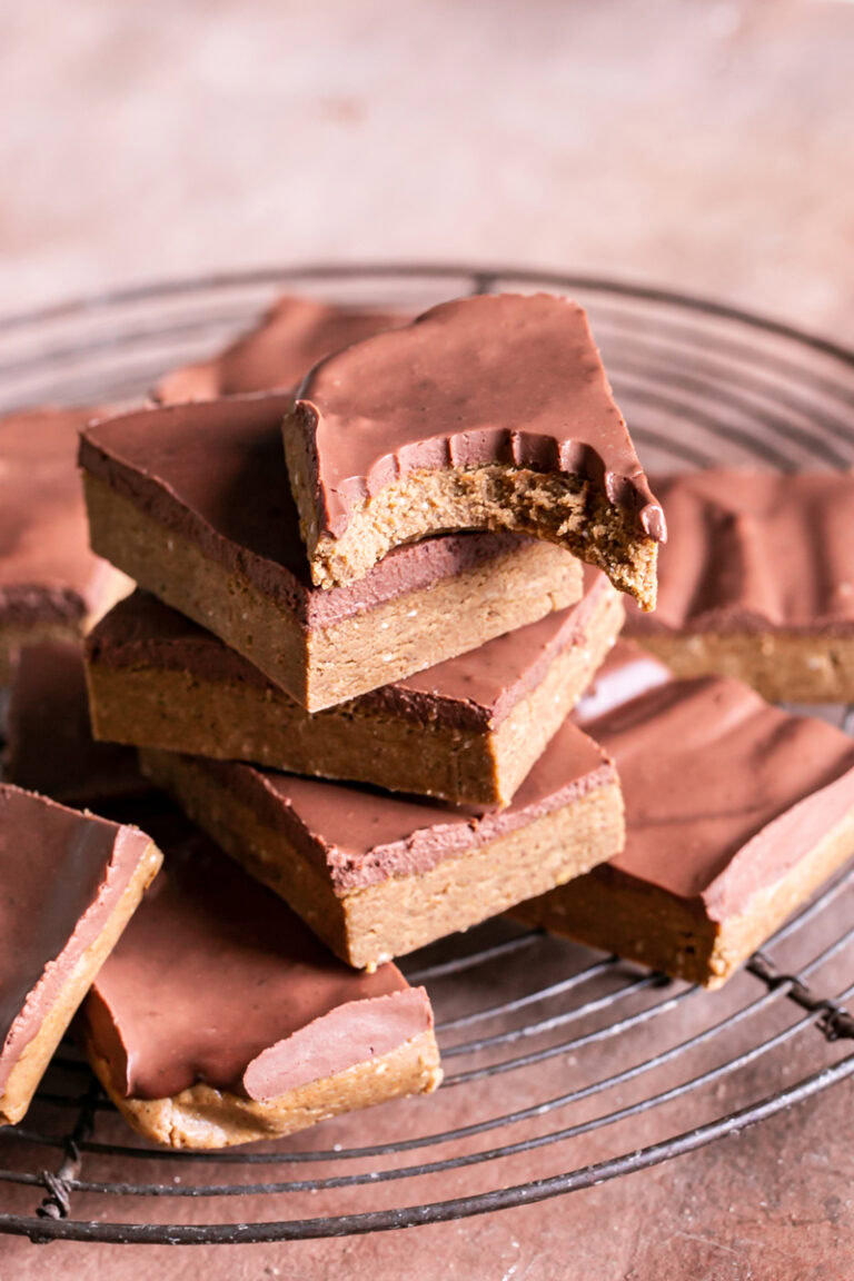 Four Seed Homemade Vegan Protein Bars stacked on a wire cooling rack the top one with a bite taken out of it