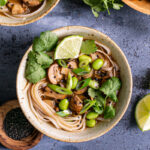a close up of one of the bowls of mushroom pho with another bowl peeking in the corner and the bowl of fresh cilantro peeking in the other corner