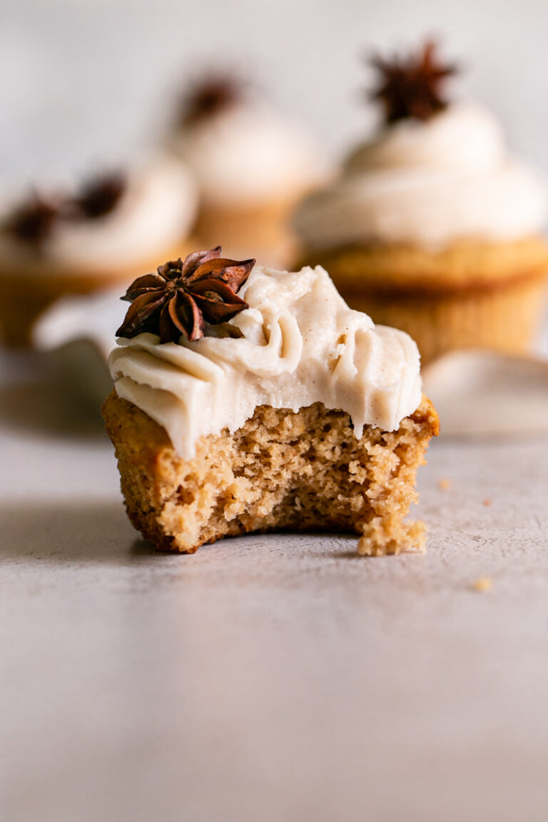 one chai cupcake in the front with a bite taken out of it and other chai cupcakes blurred in the background