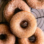 grain free cinnamon sugar donuts on a round wire cooling rack stacked on top of one another