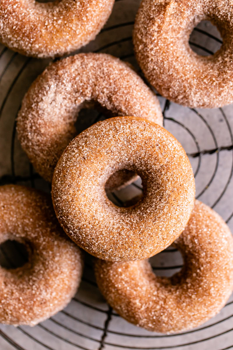 grain free cinnamon sugar donuts on a round wire cooling rack stacked on top of one another