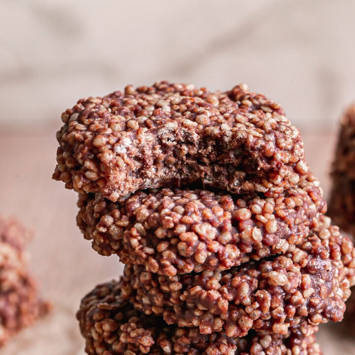 close up of Crispy Quinoa Cacao Cookies stacked on top of one another, the top one with a bite taken out of it