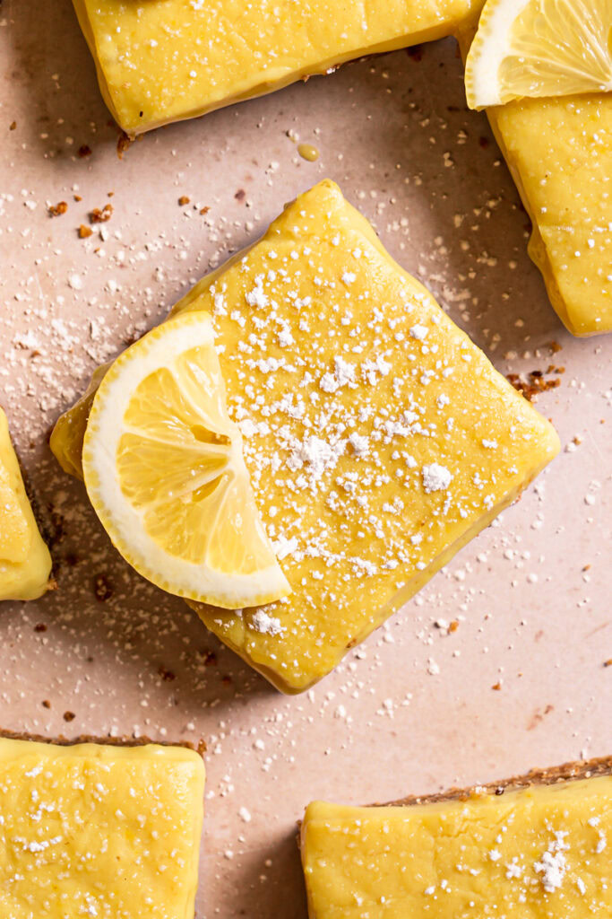 close up overhead shot of lemon bar dusted with powdered sugar and garnished with a lemon slice