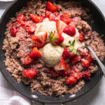 a skillet of strawberries and cream breakfast quinoa topped with fresh strawberries and banana nice cream sprinkled with chia seeds