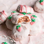 3/4 photo of strawberries and cream qunioa cookies stacked on top of one another, the top one with a bite taken out if it to reveal the crispy inside