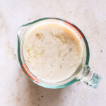a glass measuring cup filled with flax milk mixed with apple cider vinegar
