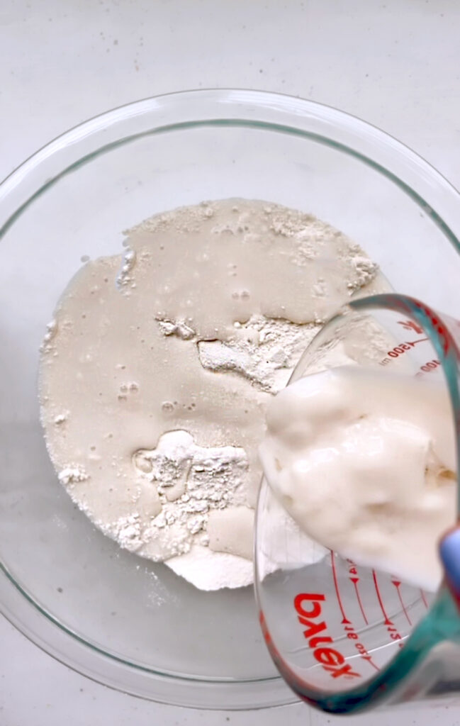 pouring the vegan buttermilk into a bowl of flour