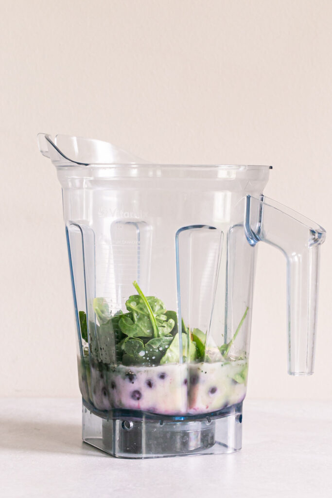 all of the blueberry spinach spirulina smoothie ingredients added to a blender