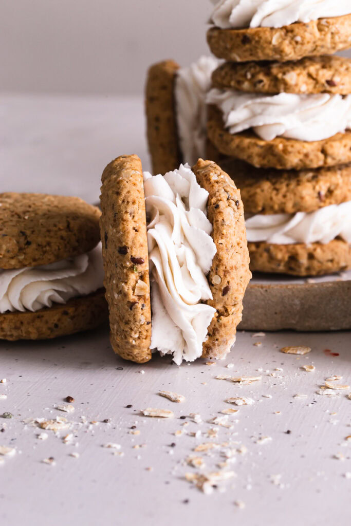 close up of a oatmeal cream sandwich cookie on it's side with stacked cookie sandwiches in the background