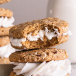 two oatmeal sandwich cookies stacked on top of one another with a bite taken out of the top one