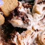 action close up shot of dipping the gluten-free graham cracker in the s'mores dip