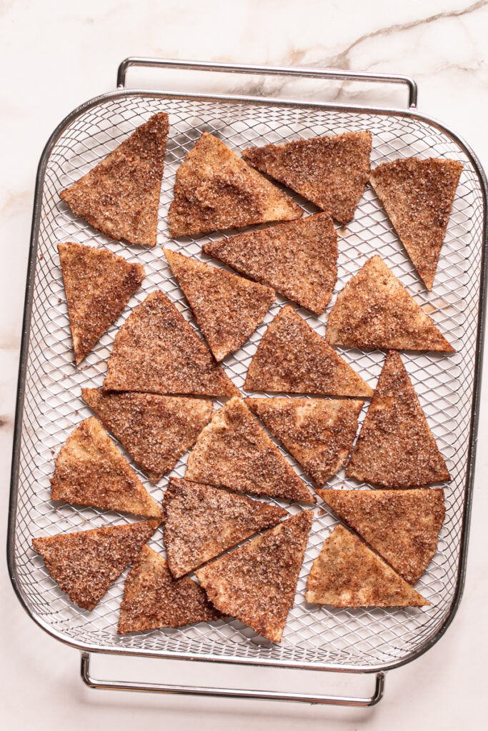 un-fried tortilla triangles coated in cinnamon sugar in the air fryer basket