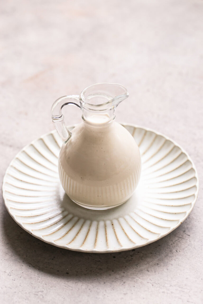 creamy tahini dressing in a glass oil bottle on a plate