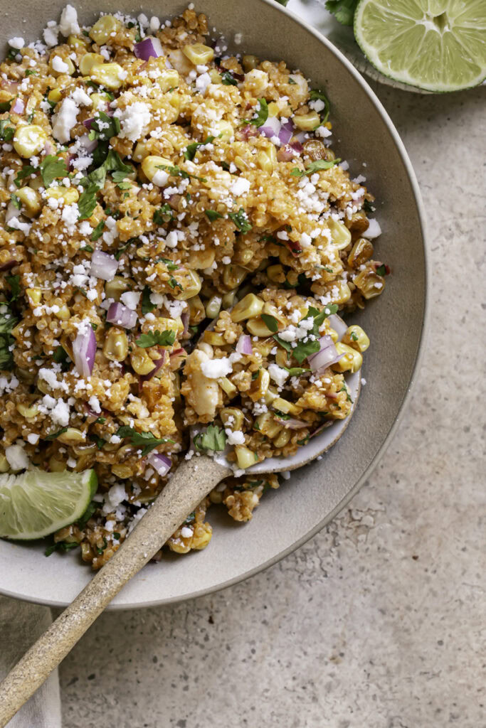 close up overhead shot of a bowl of Dairy-Free Mexican Street Corn Quinoa Salad with a spoon in it.